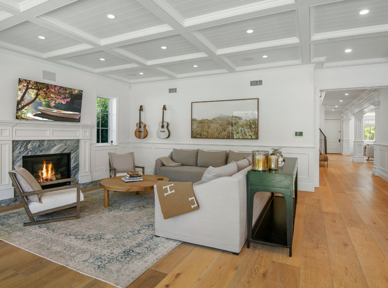 Living room area with white beamed ceiling, recessed lights, fireplace and light hardwood floors