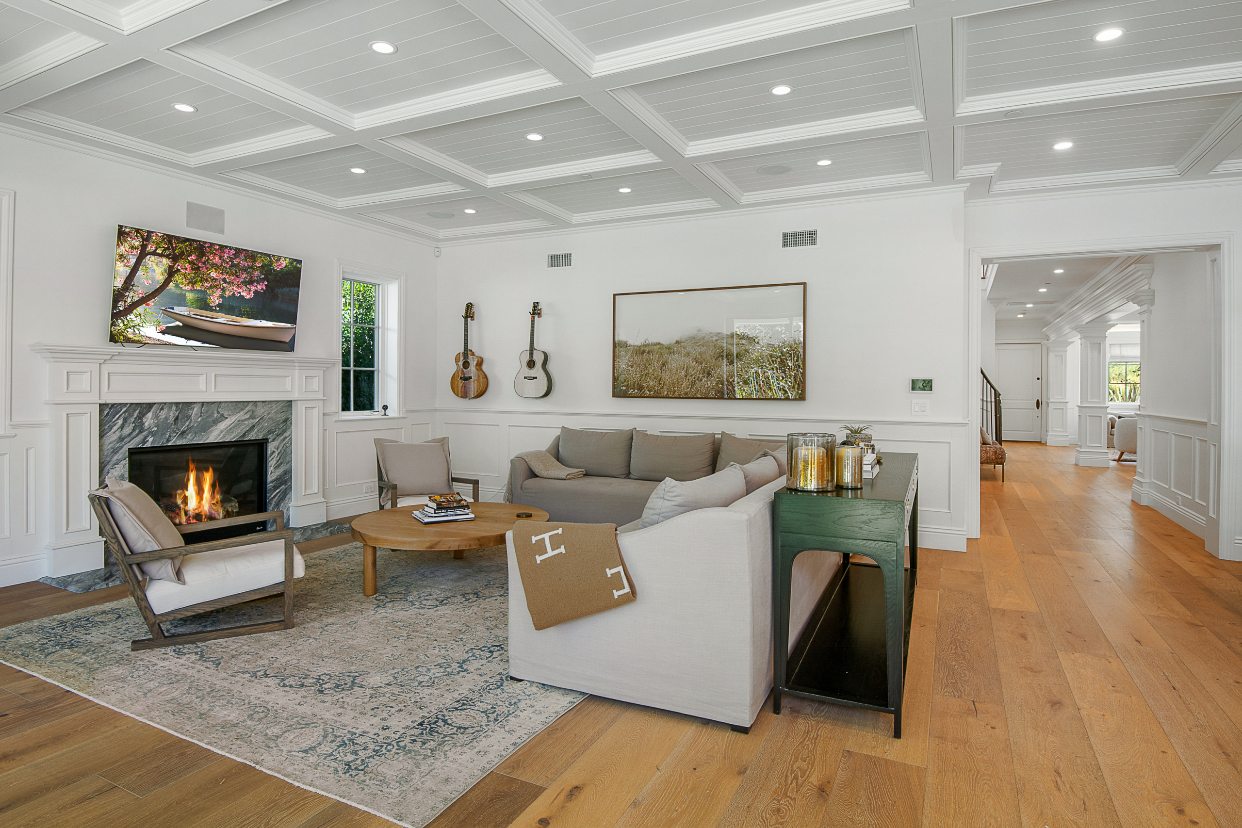 Living room area with white beamed ceiling, recessed lights, fireplace and light hardwood floors