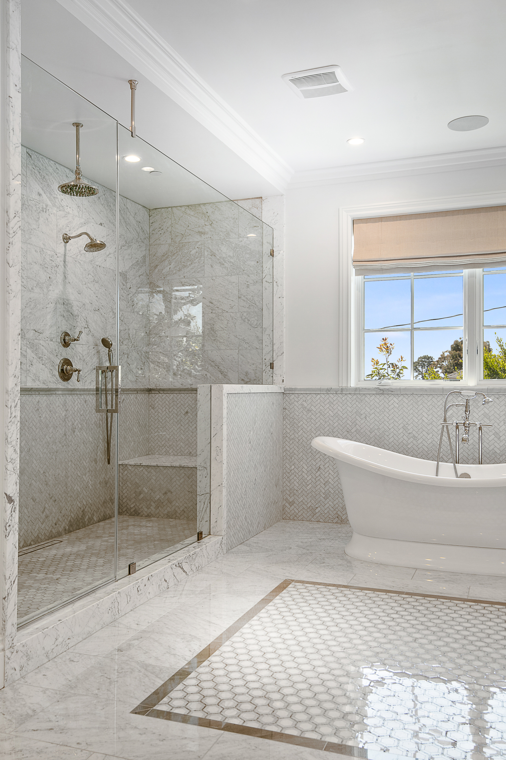 Bathroom with large walk-in shower with seating, soaker tub and window. Marble and grey and white tile