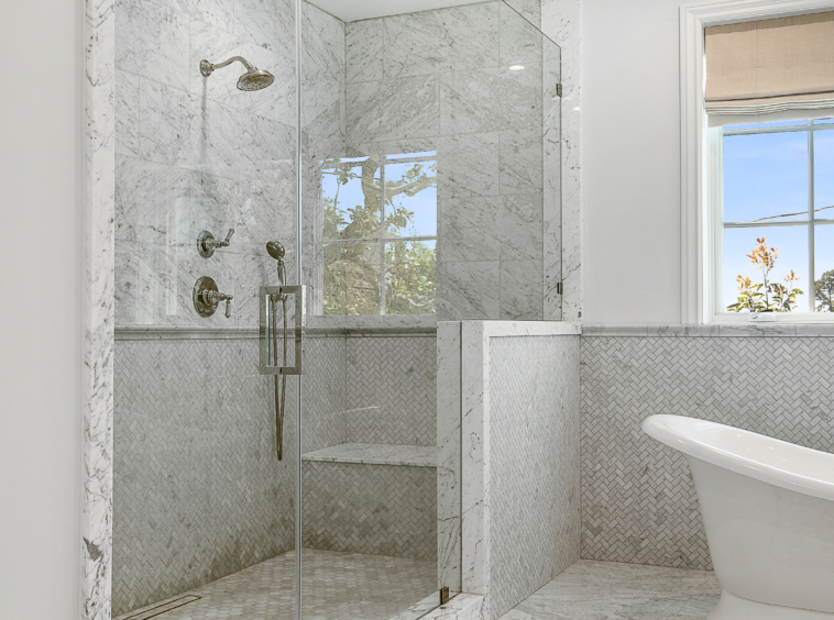 Bathroom with large walk-in shower with seating and soaker tub. Marble and grey and white tile