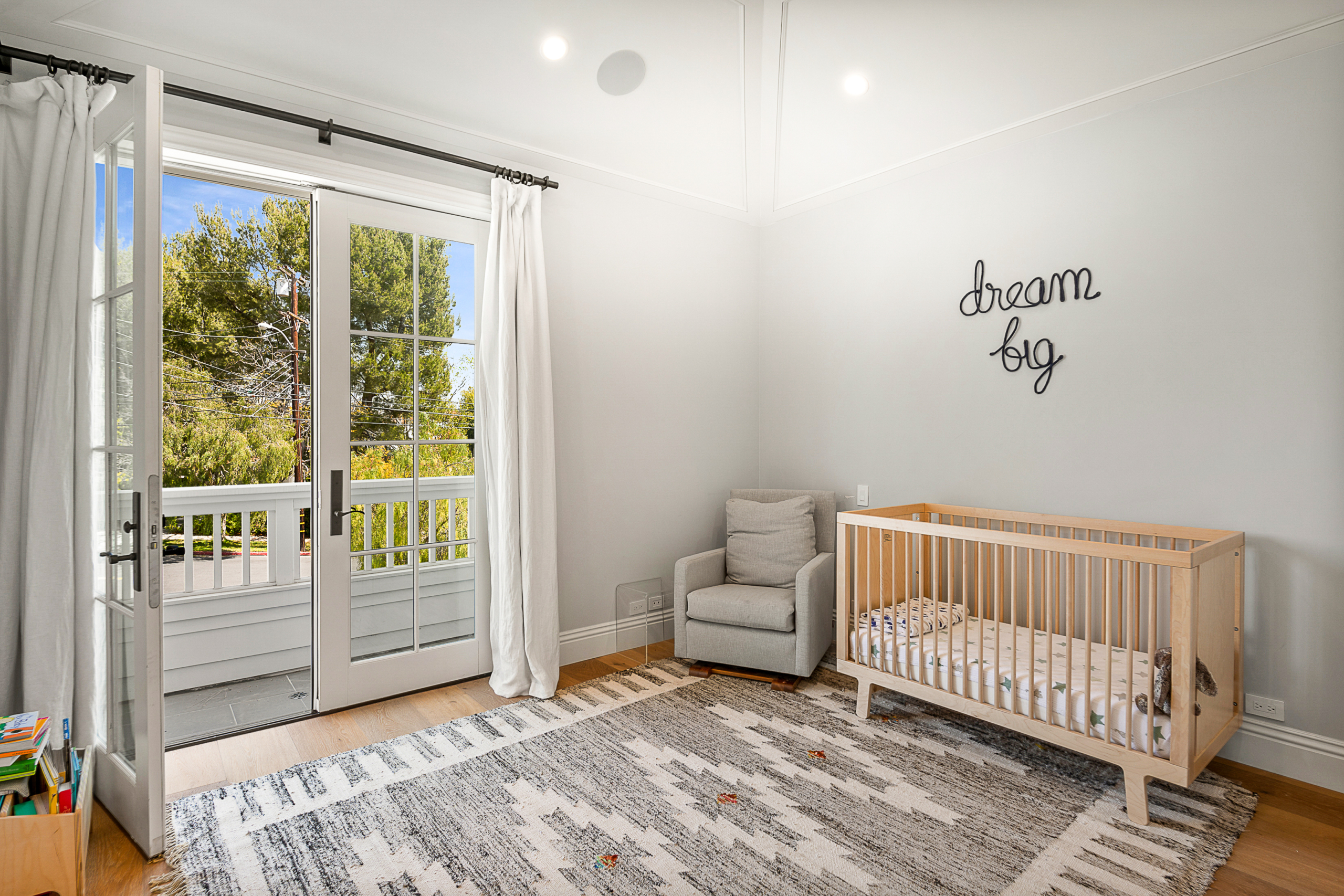 Child's bedroom with crib and French doors opening to balcony