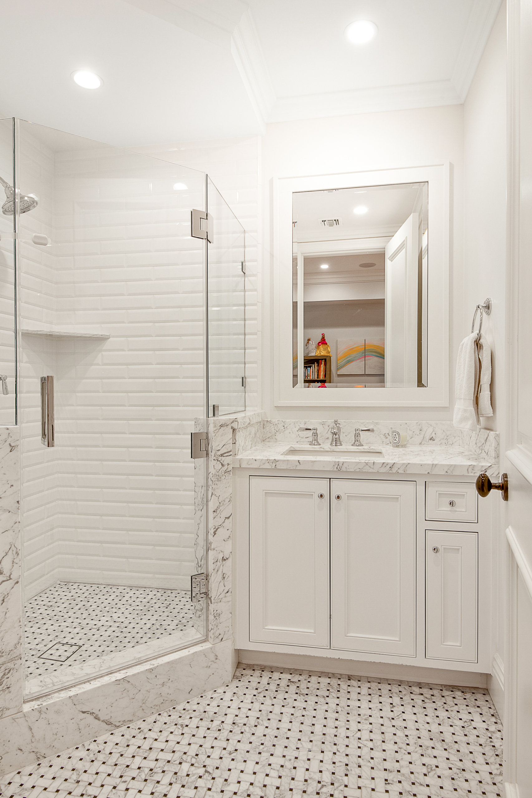 White bathroom with walk-in shower and black and white tile and marble