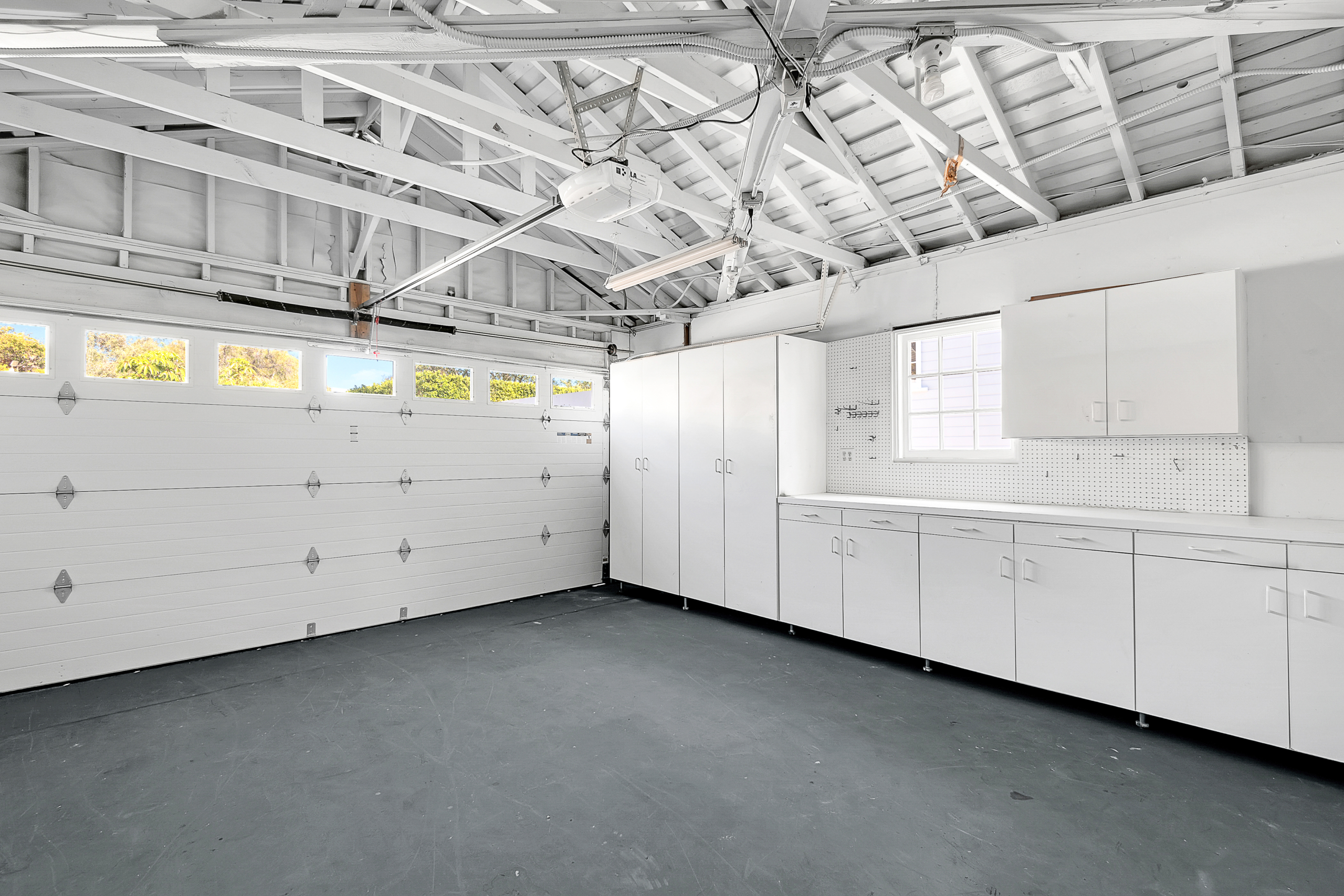 View of bright white garage with full wall of cabinets