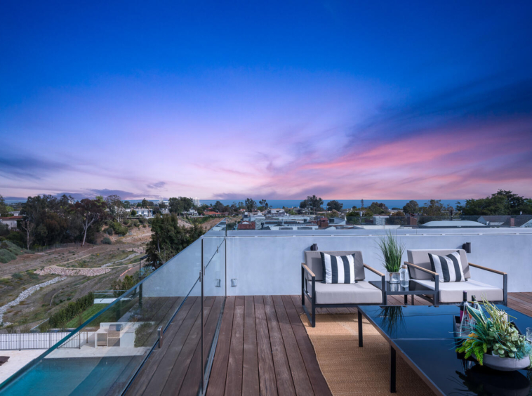 View of rooftop entertaining space and ocean in the distance at dusk