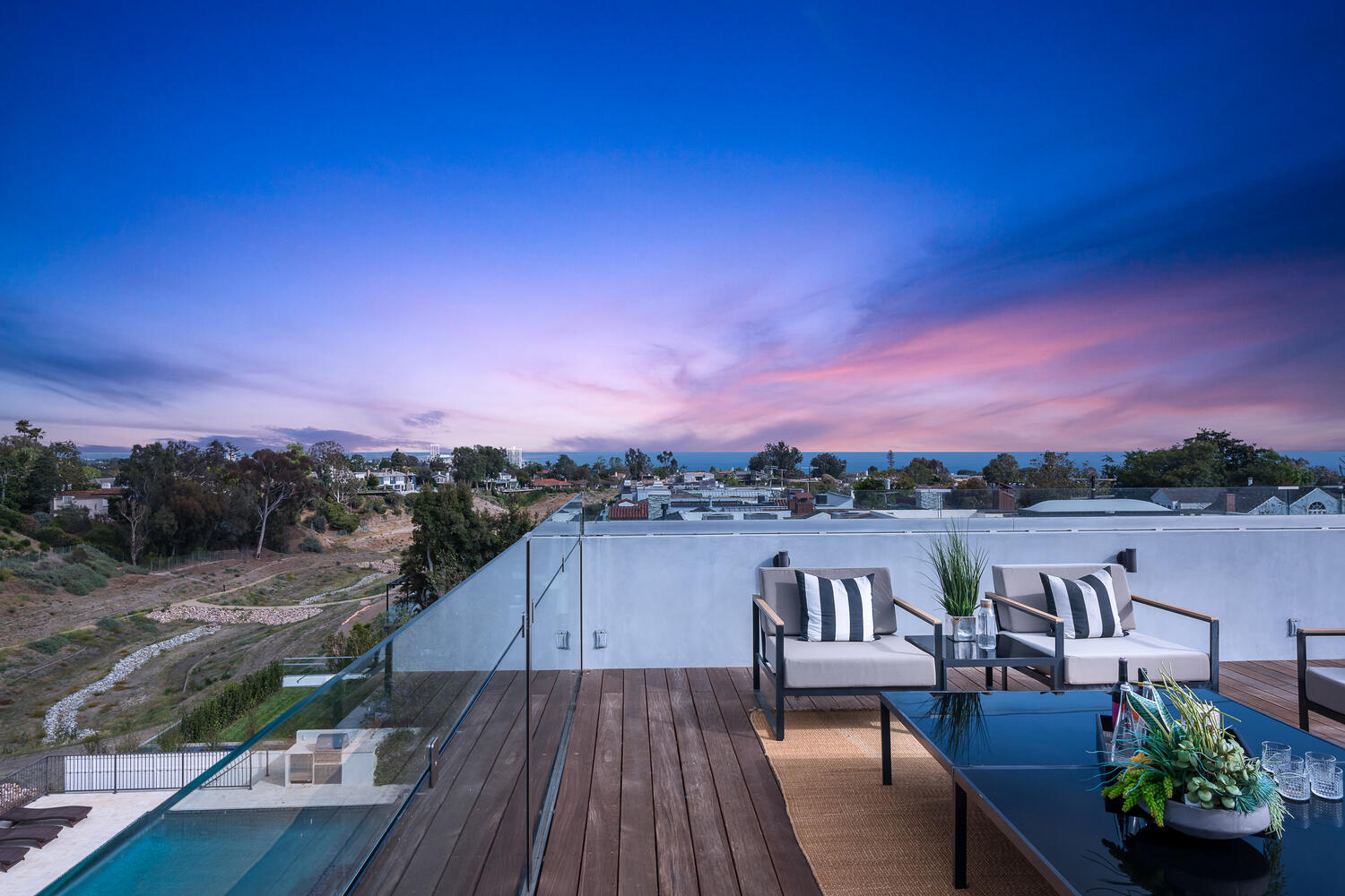 View of rooftop entertaining space and ocean in the distance at dusk