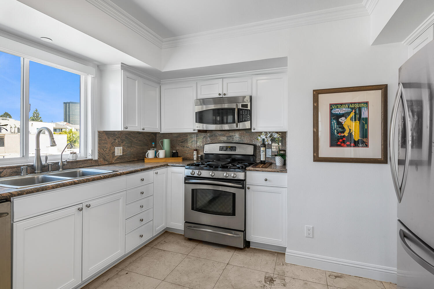 Kitchen with white cabinets, multi-colored granite and stainless appliances.