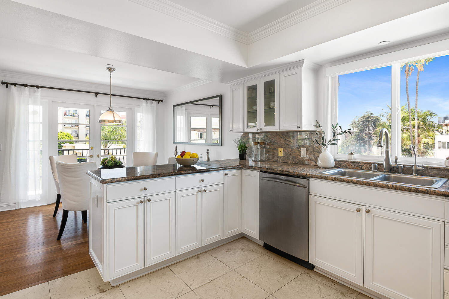 Kitchen with white cabinets, multi-colored granite and stainless appliances. View into dining area