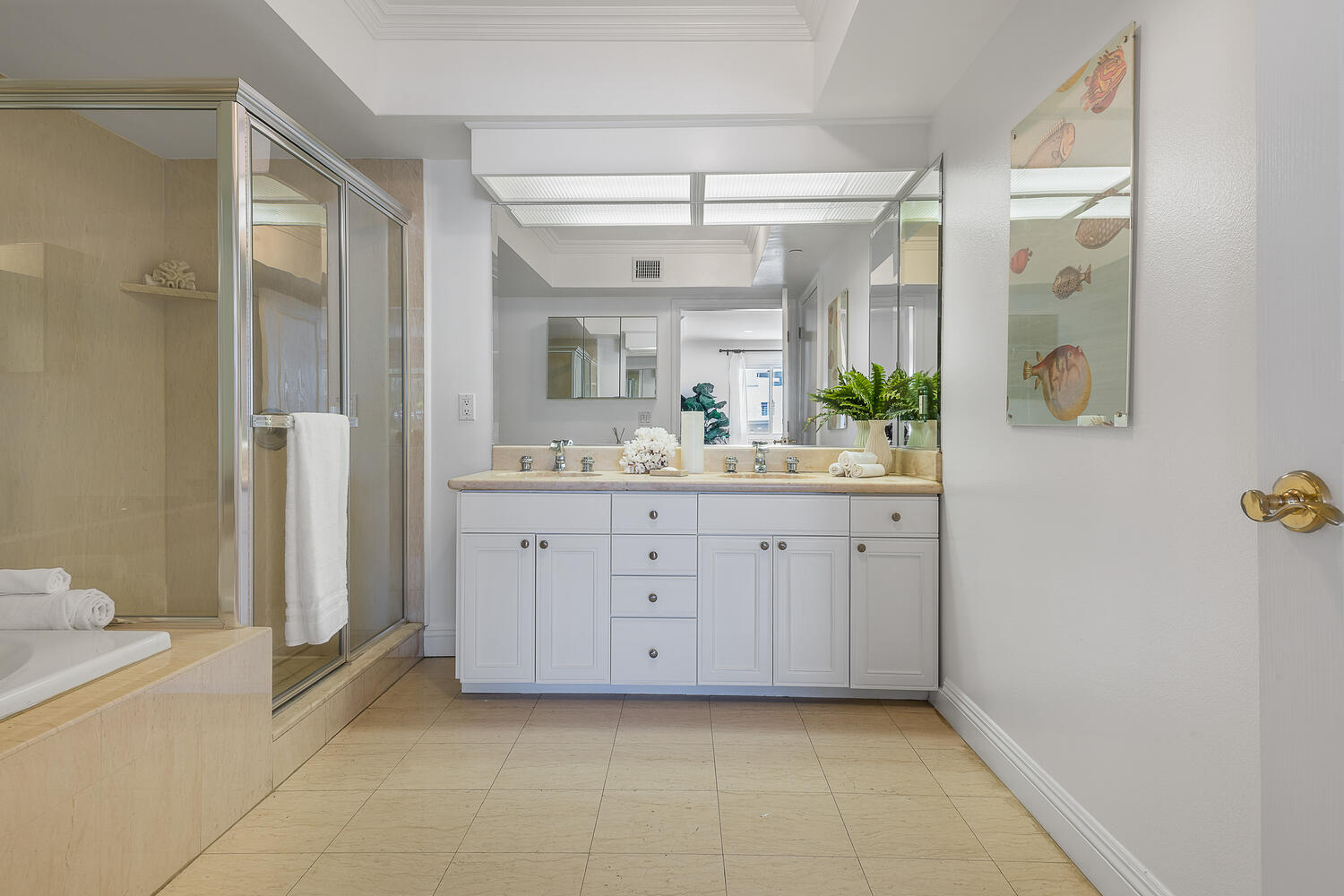 Large bathroom with light tile and two-sink vanity and walk-in shower