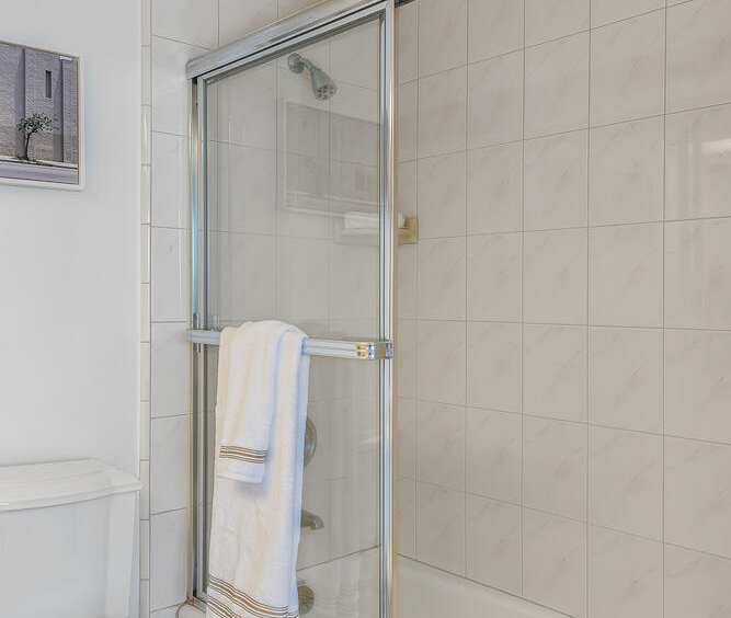 White tiled shower and tub with sliding glass door