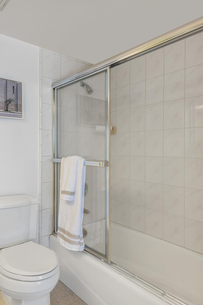 White tiled shower and tub with sliding glass door