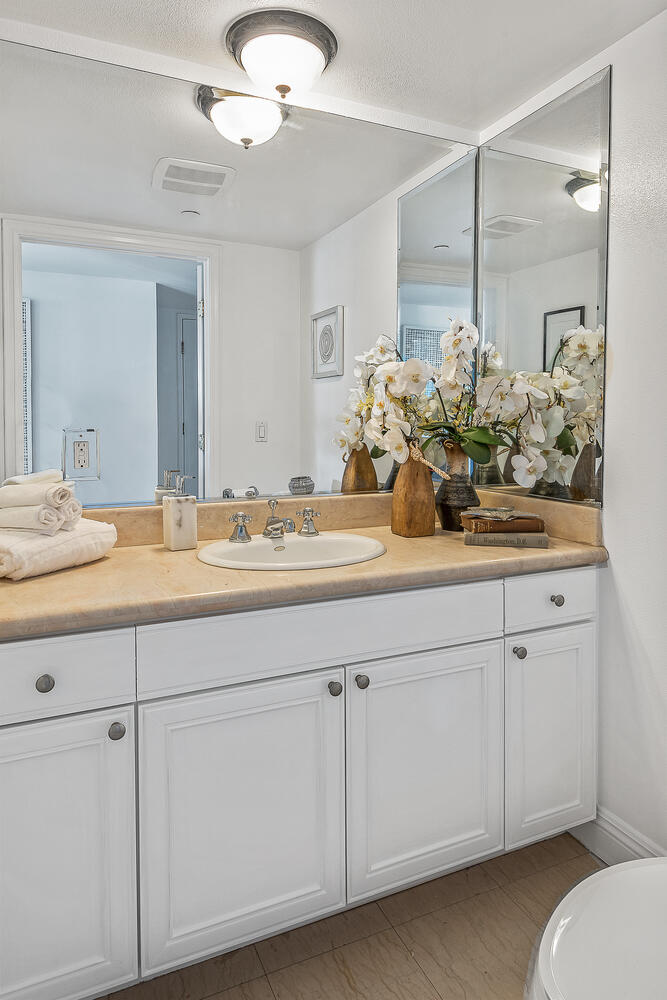 Bright bathroom vanity with white cabinets and cream marble top