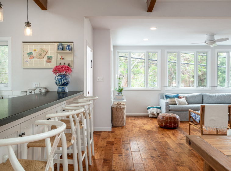 Bright dining area with wood exposed beams and hand hewn floor and view of kitchen and living room area