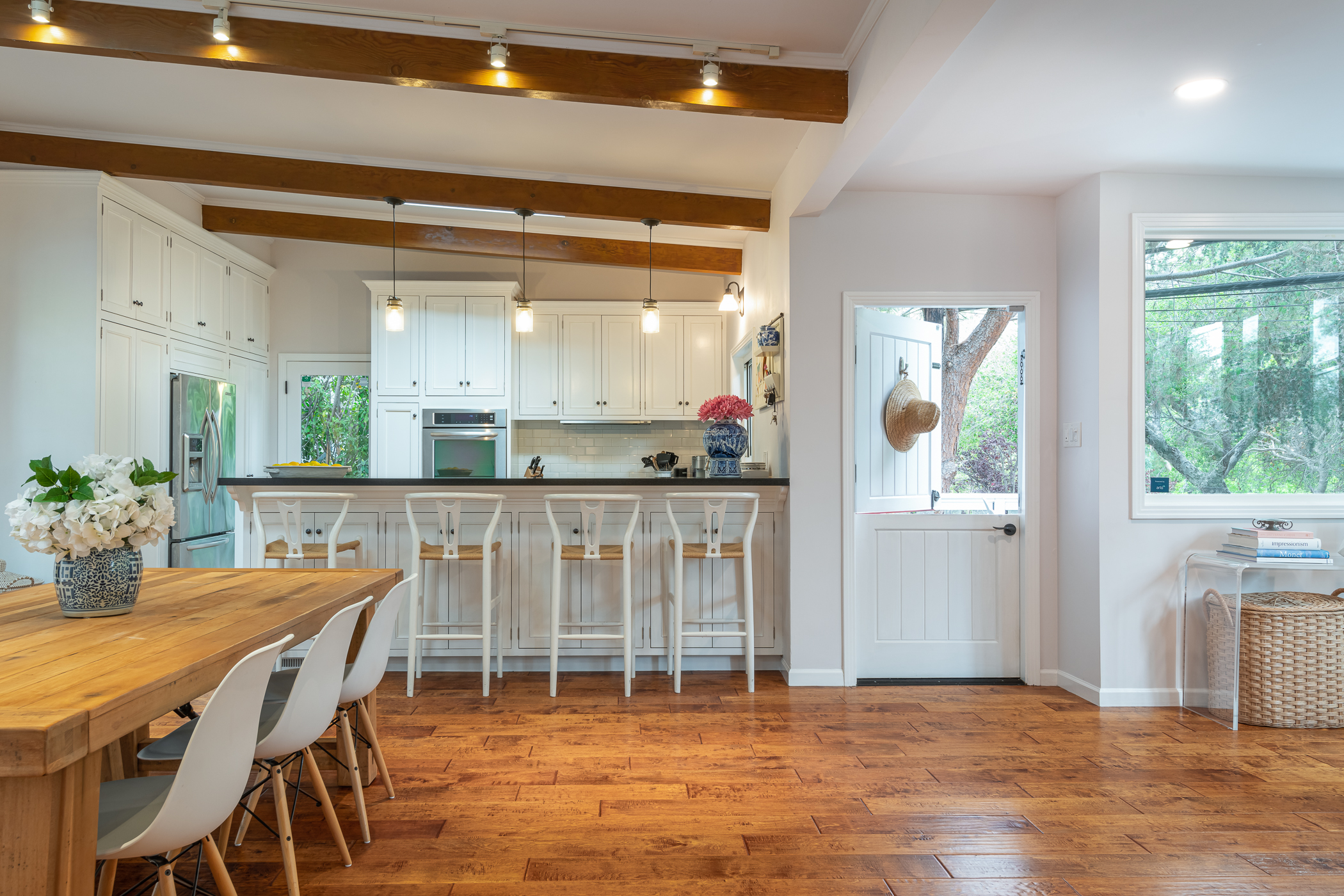 Bright dining room and kitchen with wood exposed beams and hand hewn floor