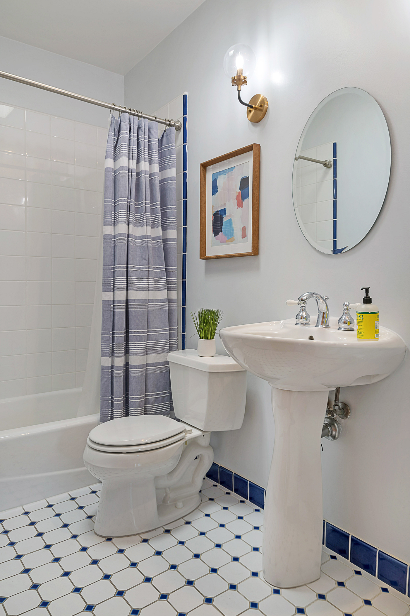 Blue and white bathroom with pedestal sink and bath/shower combo