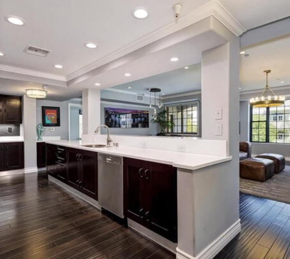 Kitchen island with modern dark cabinets and stainless appliances and open floor plan looking into living room and dinning room