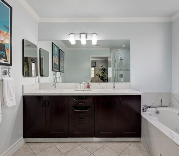 Vanity with two sinks and large mirror, partial view of tub