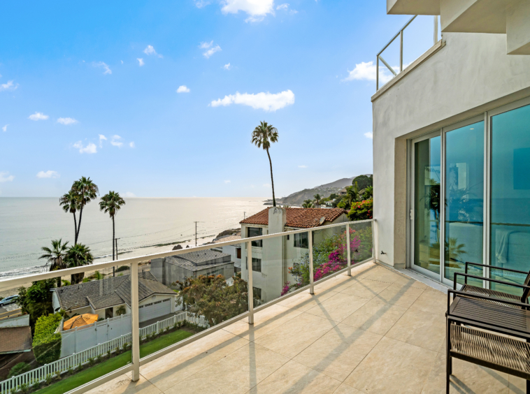 balcony with wide view of neighboring homes below and view of the ocean