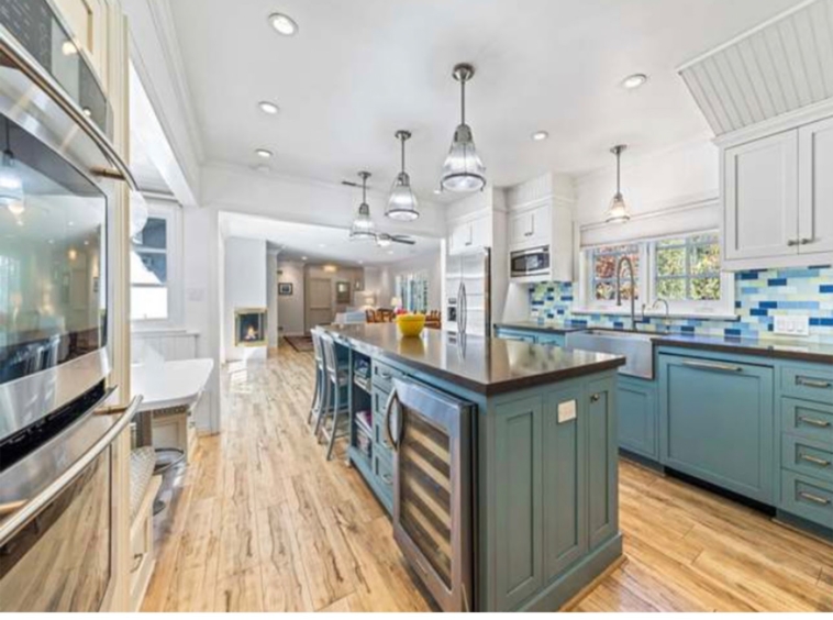 farmhouse kitchen with blue and white cabinetry plus island with wine fridge and pendant lights