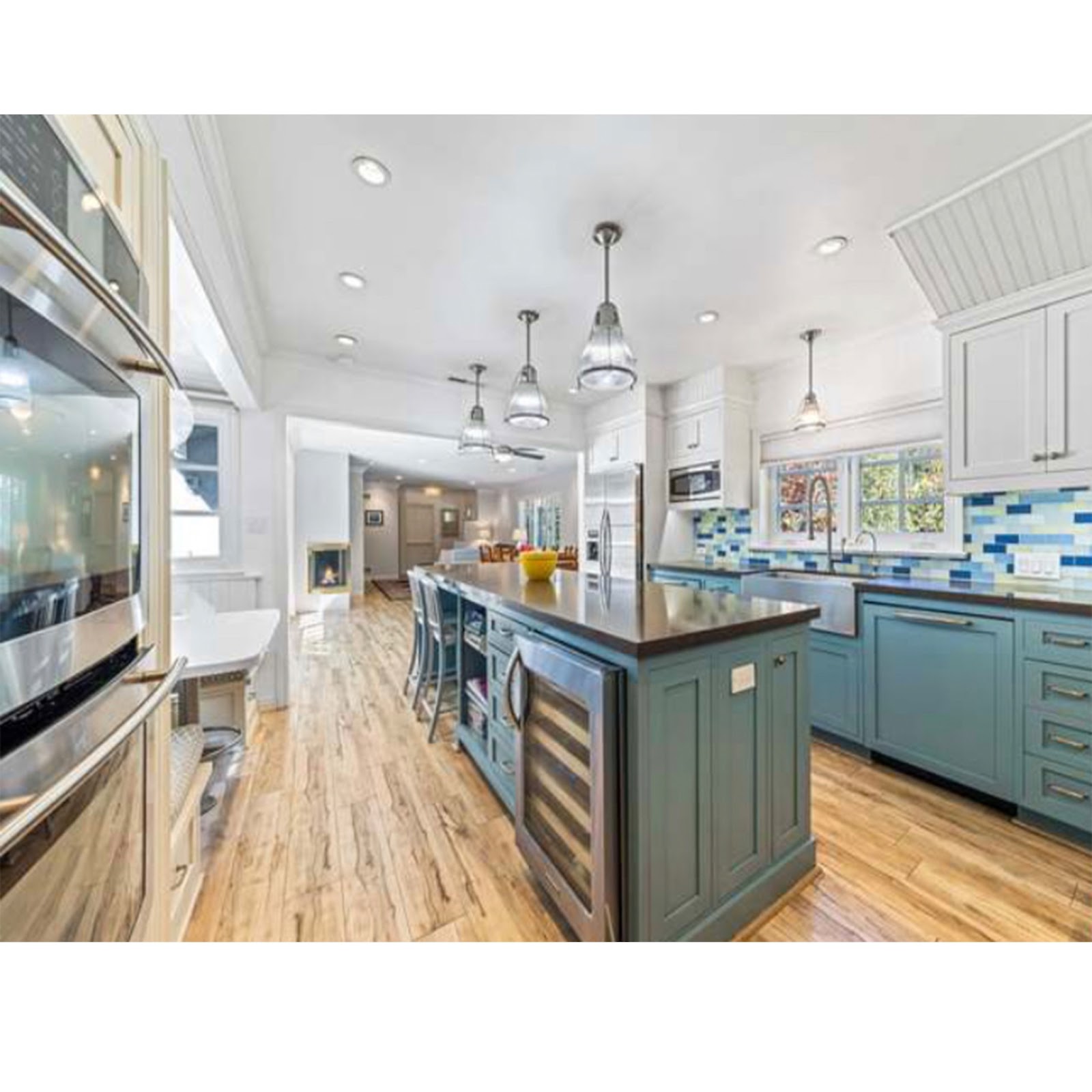 farmhouse kitchen with blue and white cabinetry plus island with wine fridge and pendant lights
