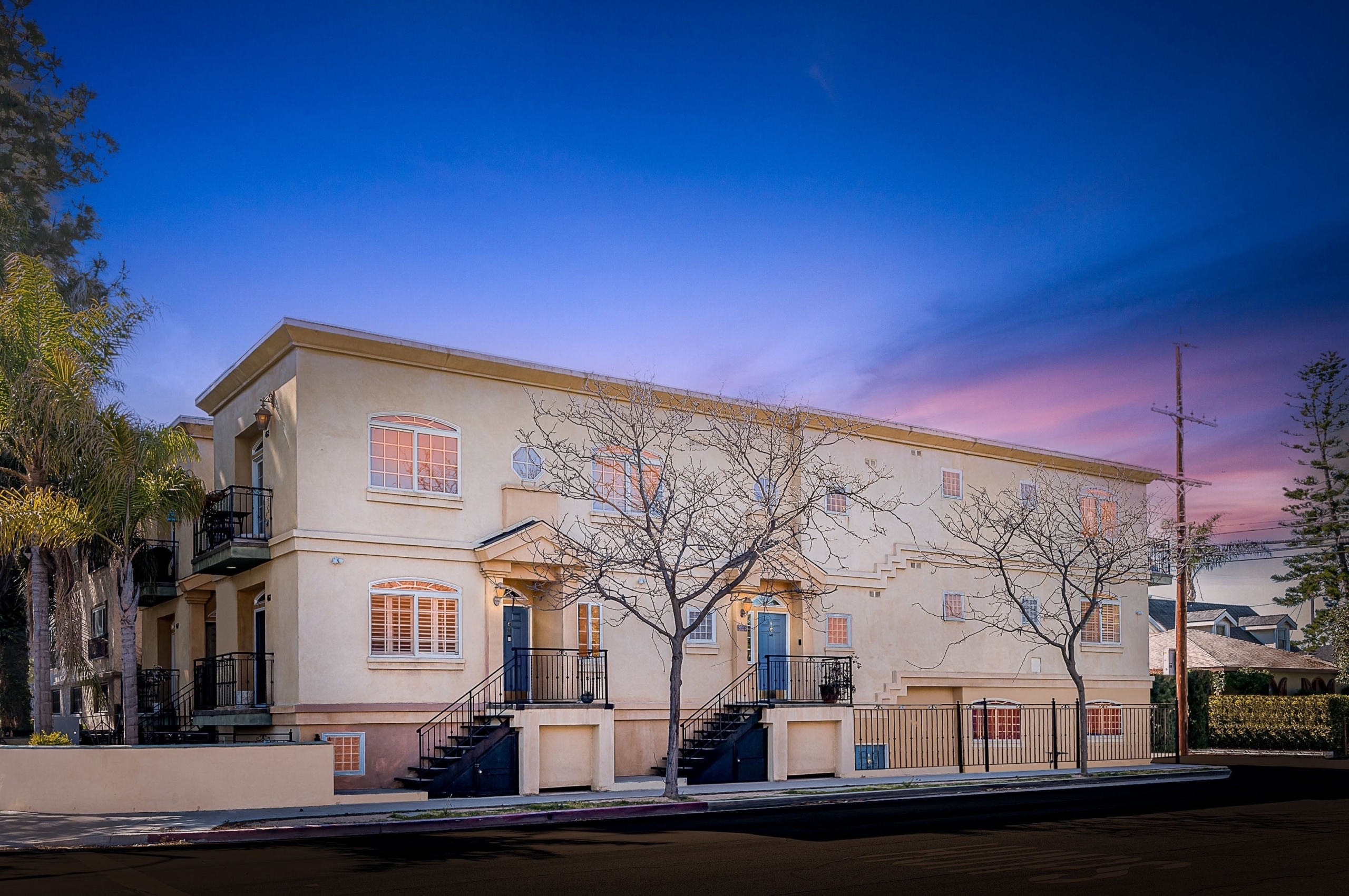 Condo with trees in front at dusk