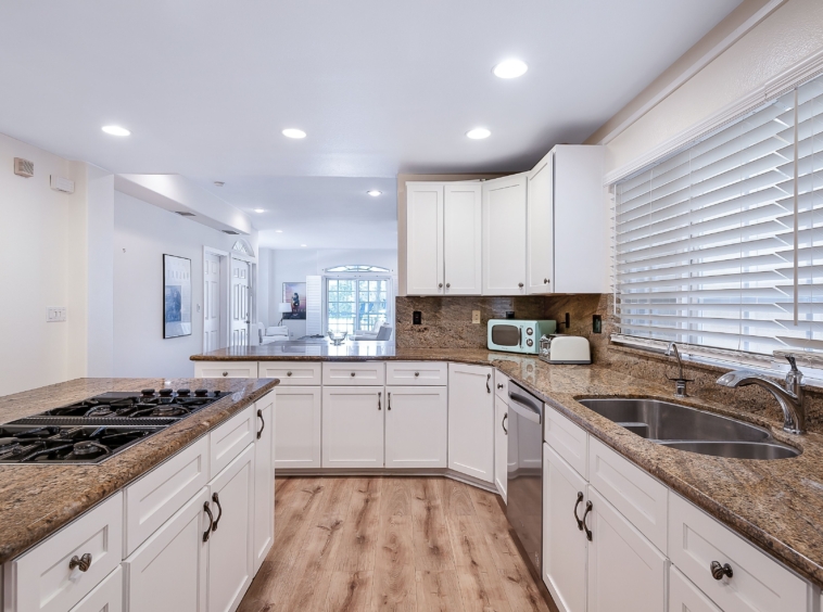 Bright white kitchen with brown granite and stainless appliances