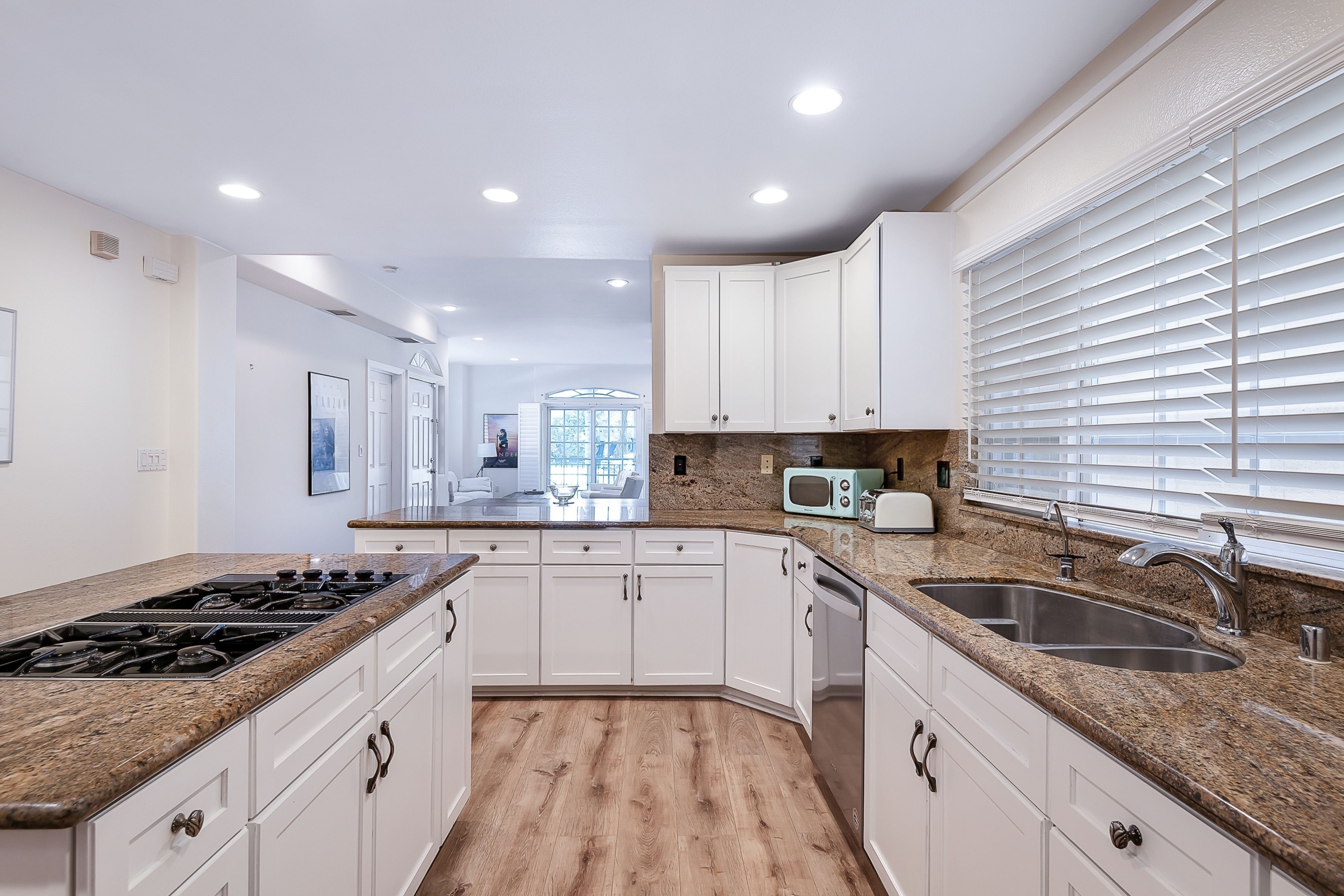 Bright white kitchen with brown granite and stainless appliances