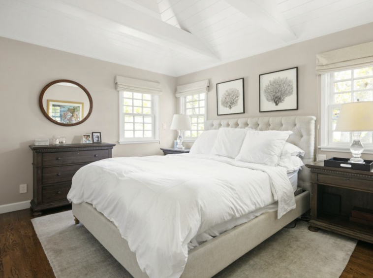 Bright white bedroom wih dark hardwood floors and vaulted beamed ceiling