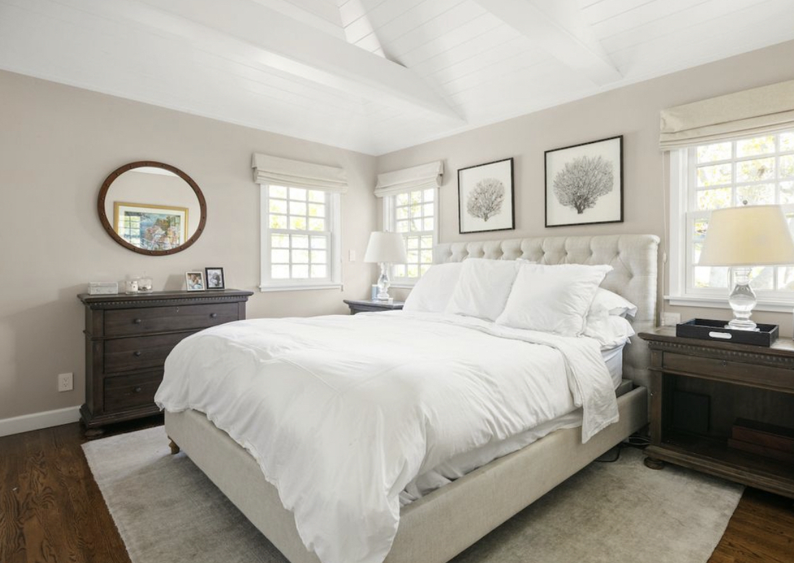 Bright white bedroom wih dark hardwood floors and vaulted beamed ceiling