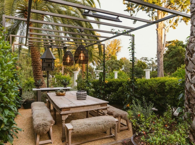 Patio area with metal pergola, hanging lamps and surrounding garden