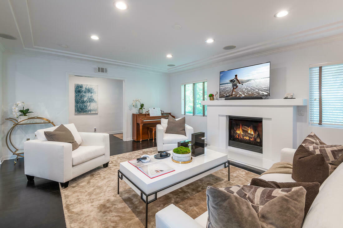 Bright white living room with fireplace and recessed ceiling and lighting and large windows