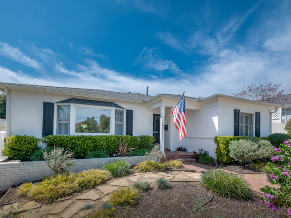 White ranch home with beautifully manicured garden, paver walk way and and stepping stones