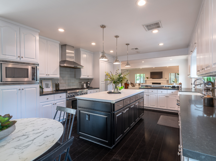 Stunning bright white kitchen with dark cabinets on island and grey granite countertops