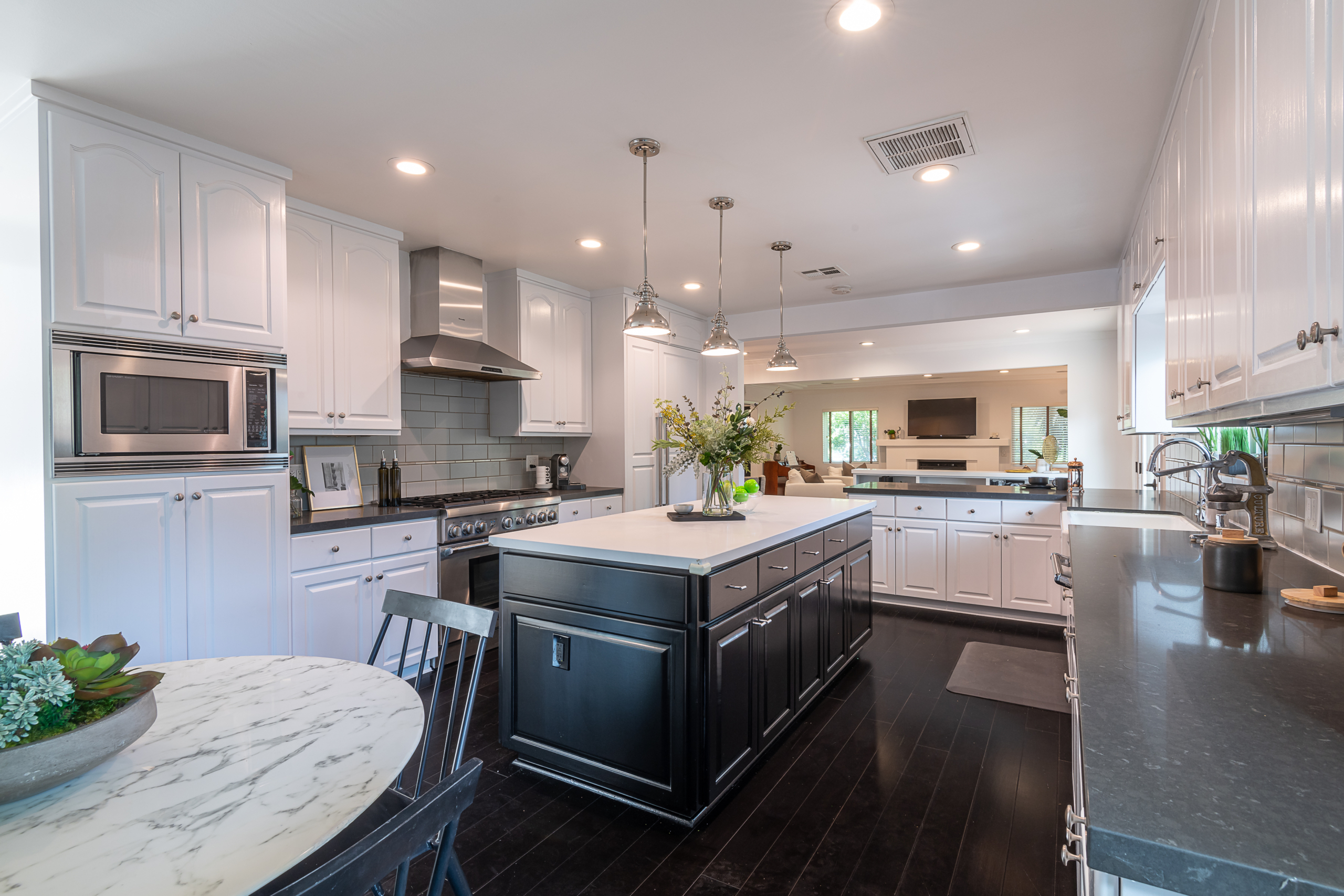 Stunning bright white kitchen with dark cabinets on island and grey granite countertops