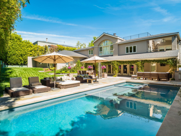 Two-story tan home with large patio and pool