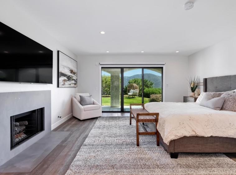 modern white bedroom with sliding glass door, fireplace and hardwood floors