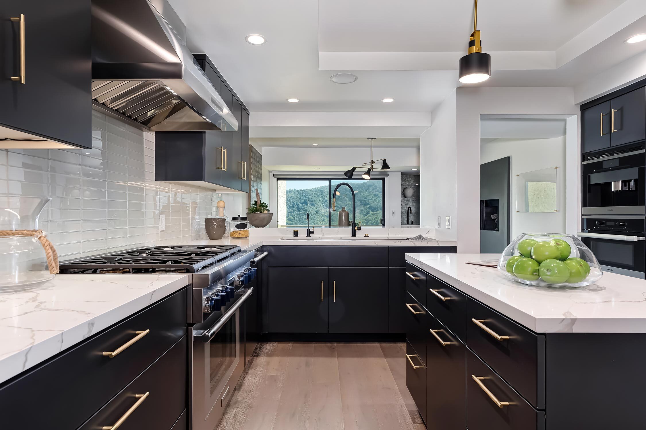 modern kitchen with white marble countertops, stainless and black appliances and black cabinets