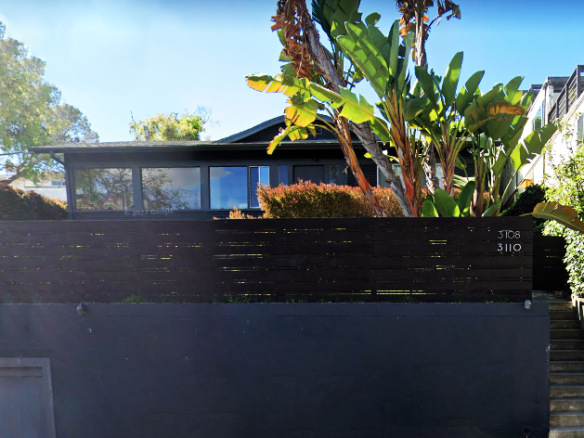 View of exterior home with palm trees and dark modern fence