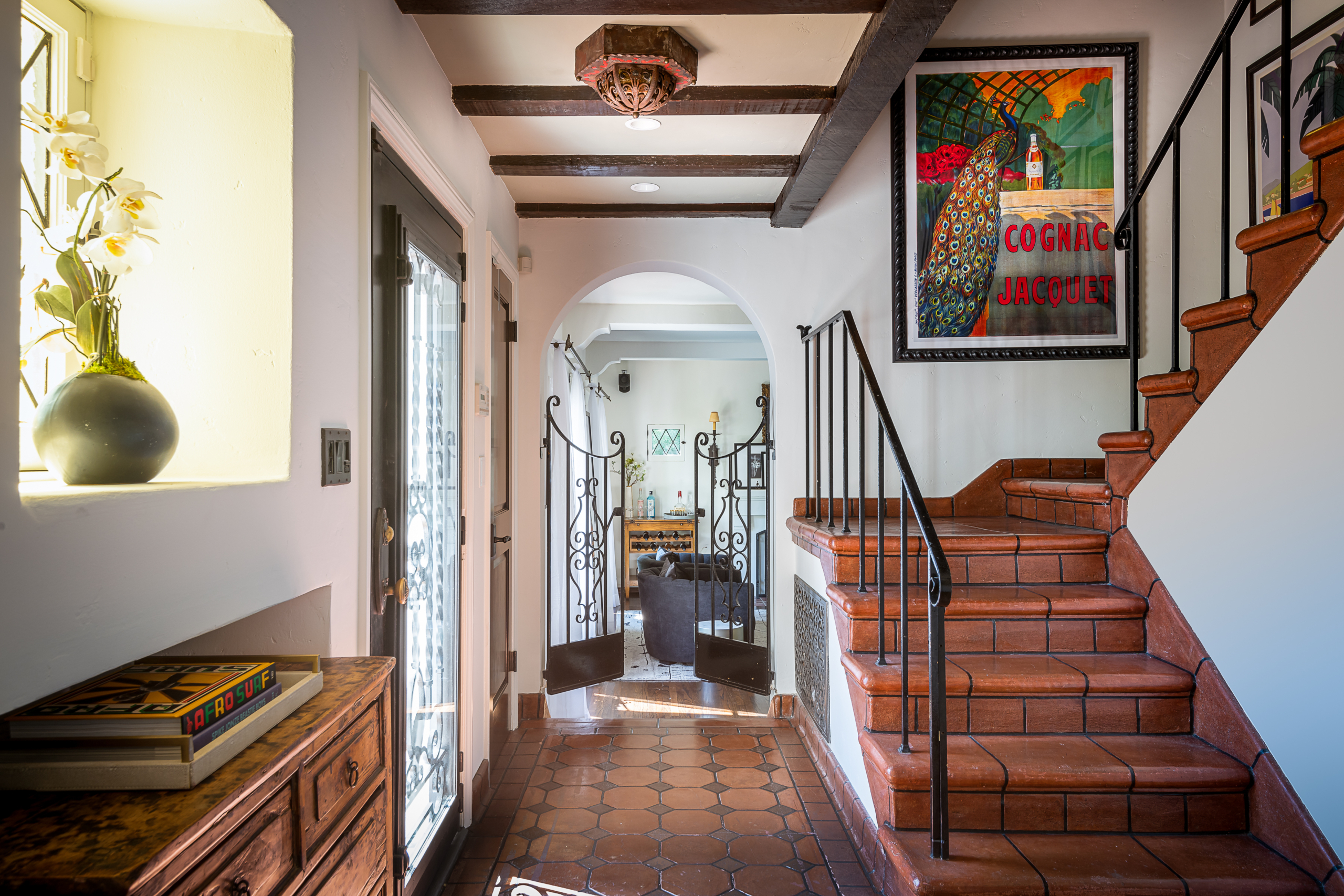 Spanish style hallway with Spanish tile flooring and stairs, hand-hewn dark beams and wrought iron railing and gate