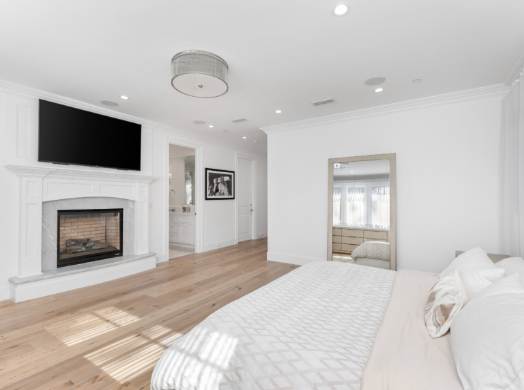 bright white bedroom with fireplace and light hardwood flooring