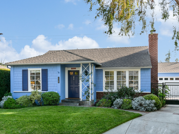 Front of blue, shingled cottage with white trim and green lawn