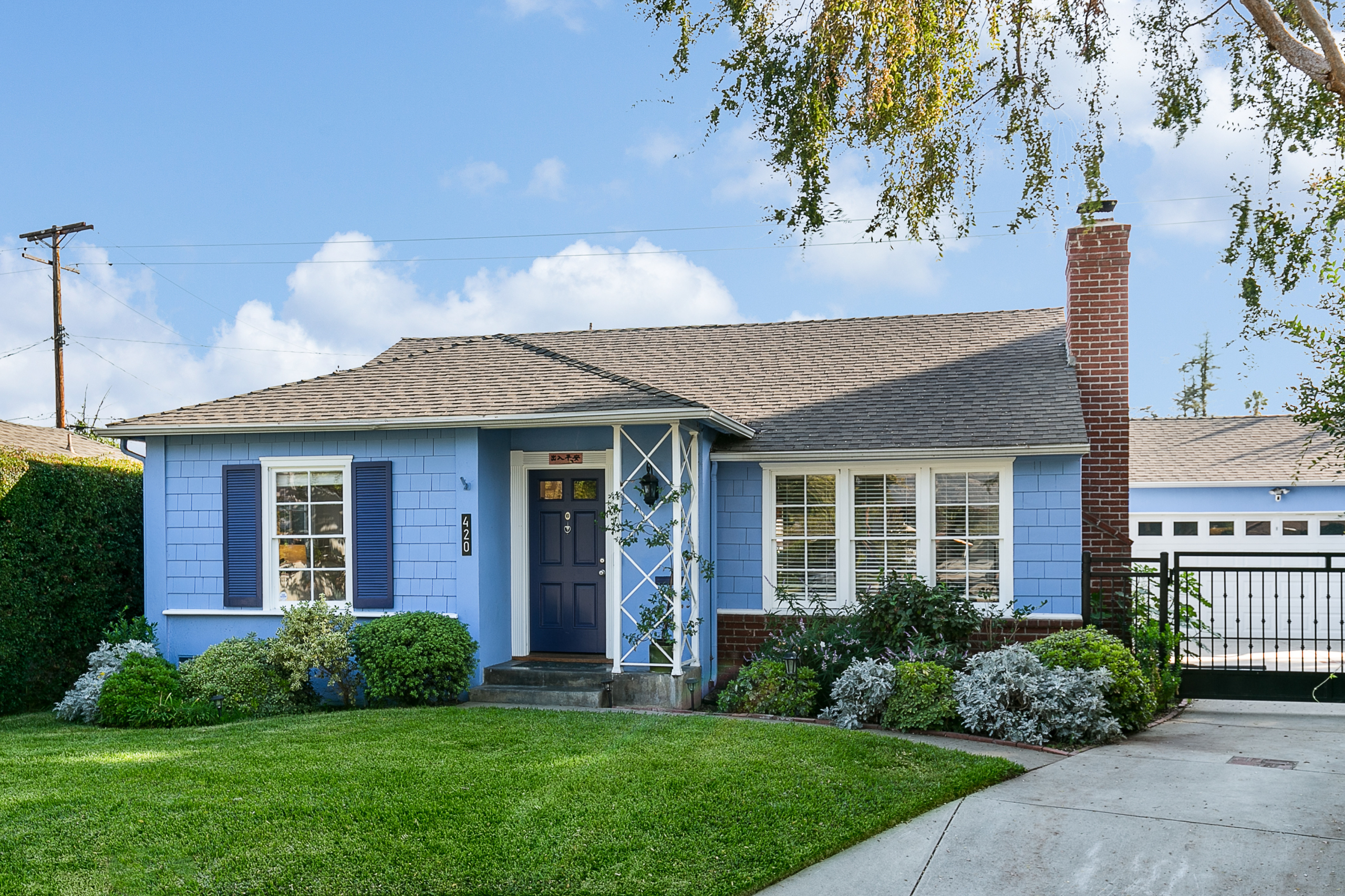 Front of blue, shingled cottage with white trim and green lawn