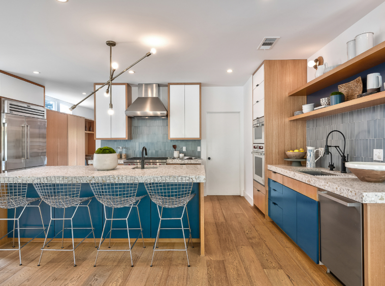 Modern kitchen with stainless appliances, blue accents and hardwood flooring.