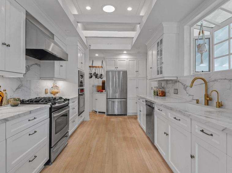 Bright, white kitchen with light hardwood flooring and stainless appliances.