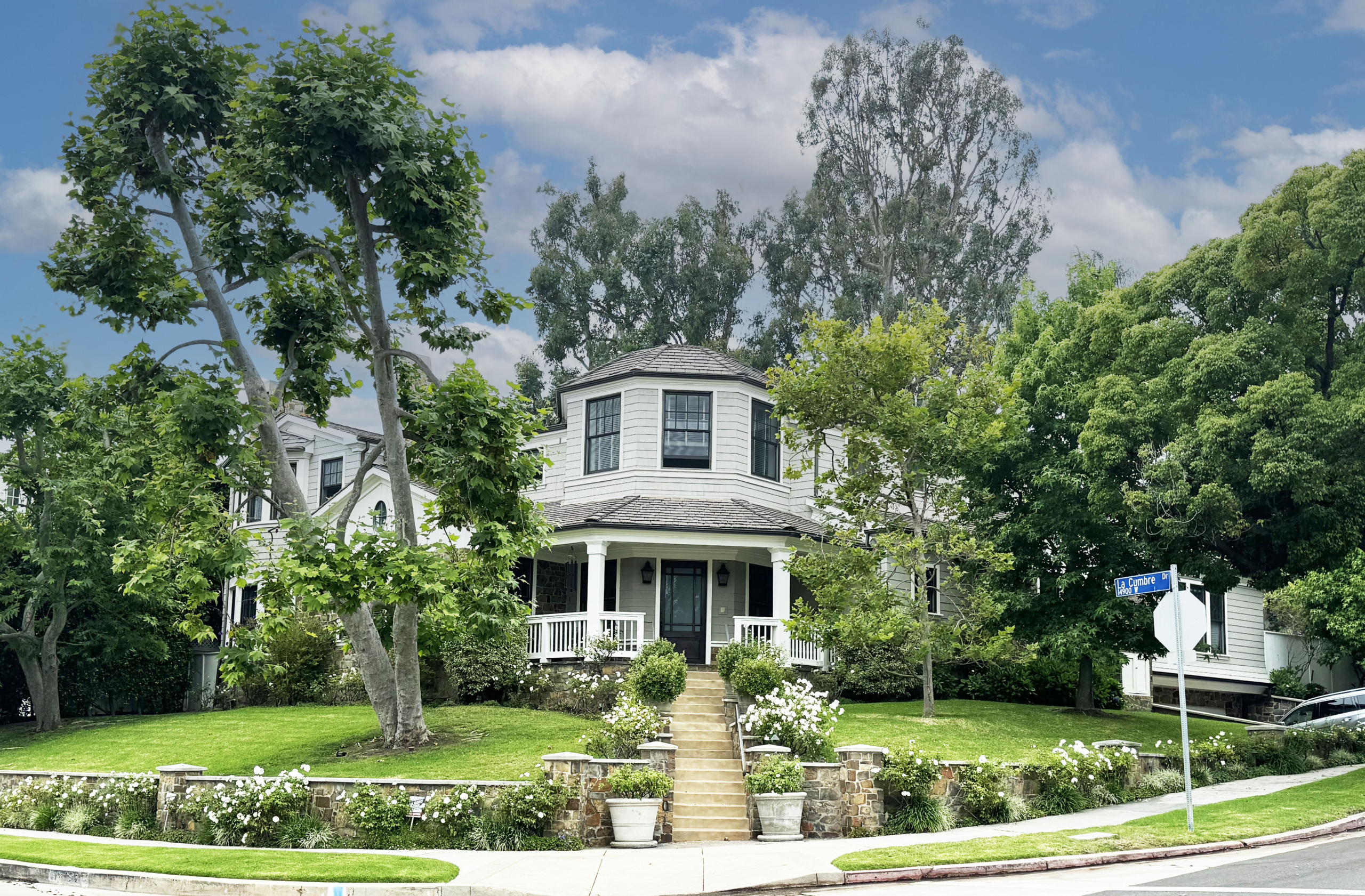 Pacific Palisades white and black traditional home on a corner lot with mature trees.