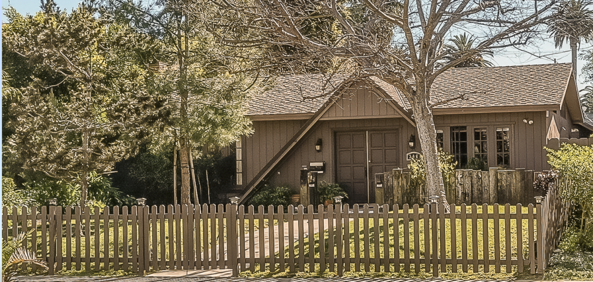 Tan colored A-framed home with green grass yard and picket fence in Santa Monica, California