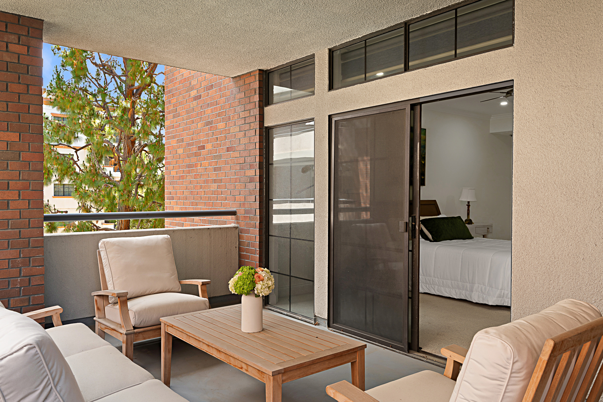 Balcony with outdoor furniture and slider door looking into bedroom.