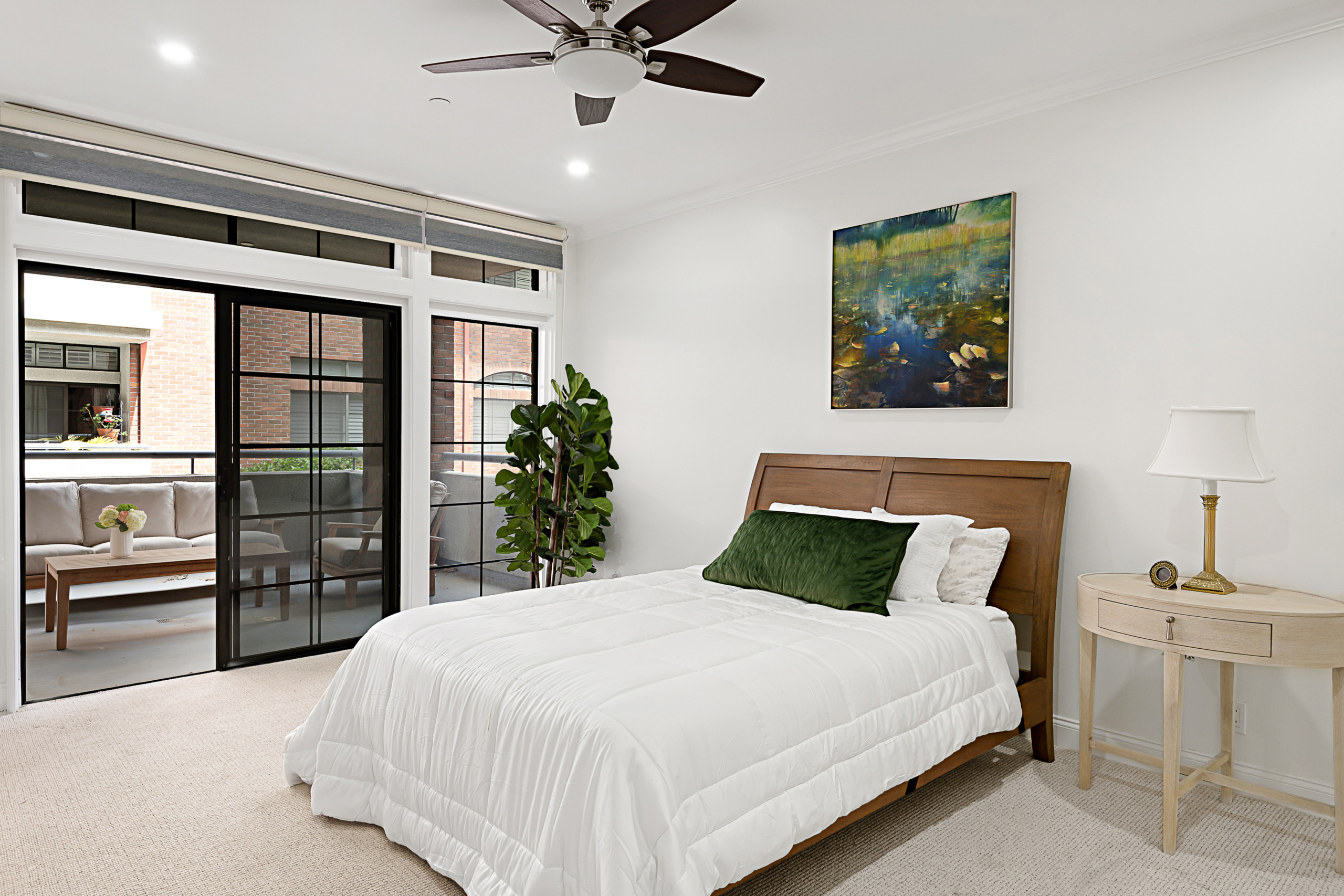 Bright condo bedroom with slider doors open to balcony.