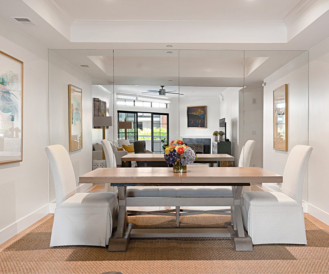 Bright white modern dining room with mirrored wall.