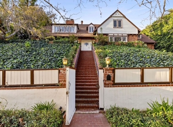 905 Napoli Drive in Pacific Palisades, CA- a view of a pitched ivy garden, retaining wall and steps leading to a two-story home.
