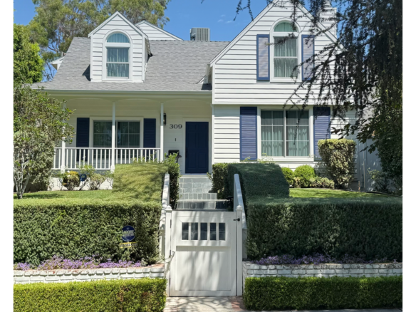 309 21st Place | Santa Monica View of he front of the white home with shutters, green lawn, large hedge and gated entrance to walkup steps and front porch.